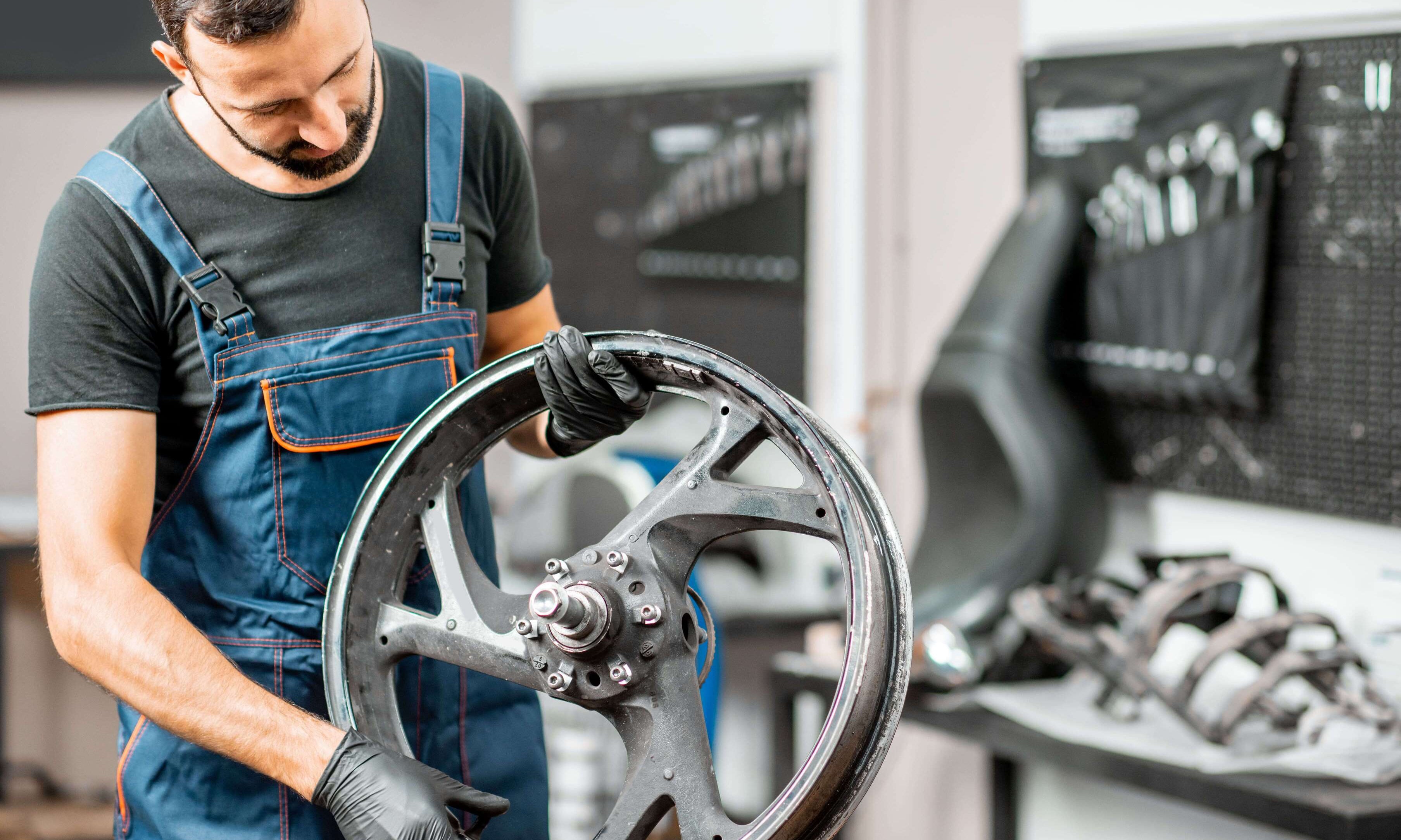 DIY rider changing a motorcycle tire in a home garage