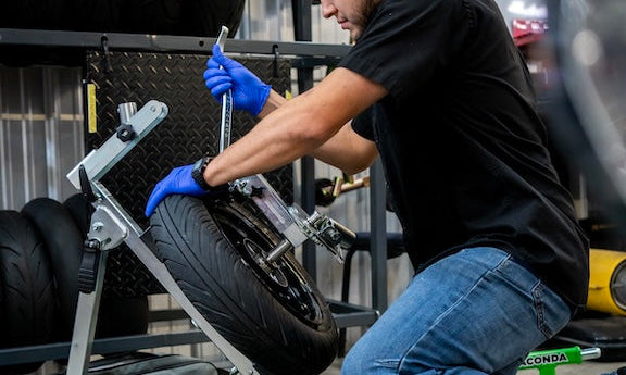 Technician changing a motorcycle tire with a Rabaconda tire changer