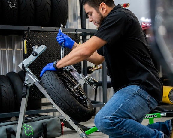 Technician changing a motorcycle tire with a Rabaconda tire changer