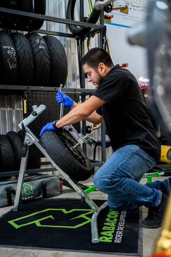 Technician changing a motorcycle tire with a Rabaconda tire changer
