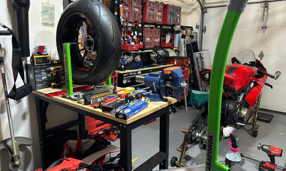 Motorcycle wheel mounted on a Rabaconda Motorcycle Wheel Balancer in a home garage, allowing a rider to accurately balance the wheel after a tire change.