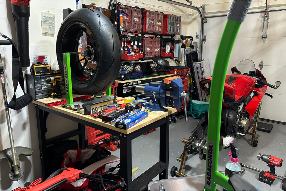 Motorcycle wheel mounted on a Rabaconda Motorcycle Wheel Balancer in a home garage, allowing a rider to accurately balance the wheel after a tire change.