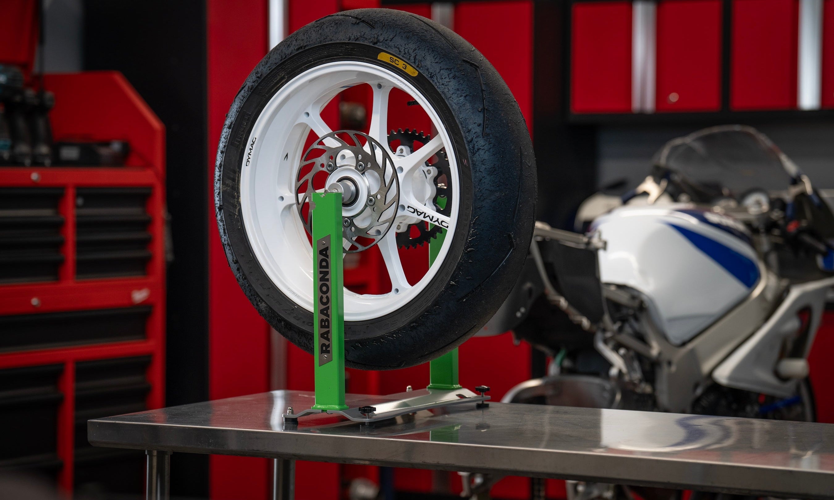 Motorcycle wheel mounted on a Rabaconda Wheel Balancer in a home garage for precise wheel balancing