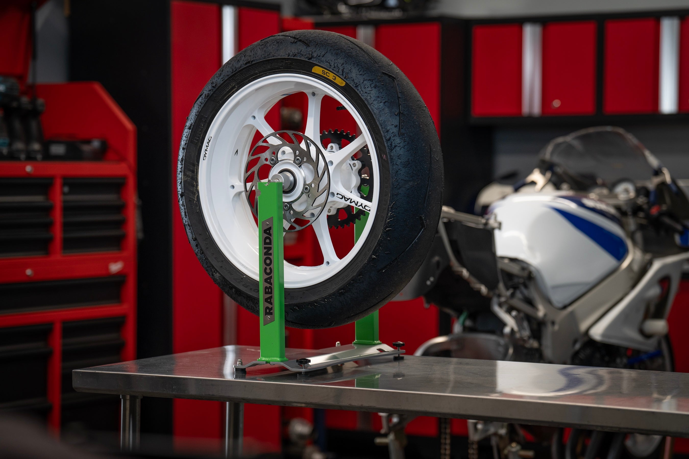 Motorcycle wheel mounted on a Rabaconda Wheel Balancer in a home garage for precise wheel balancing