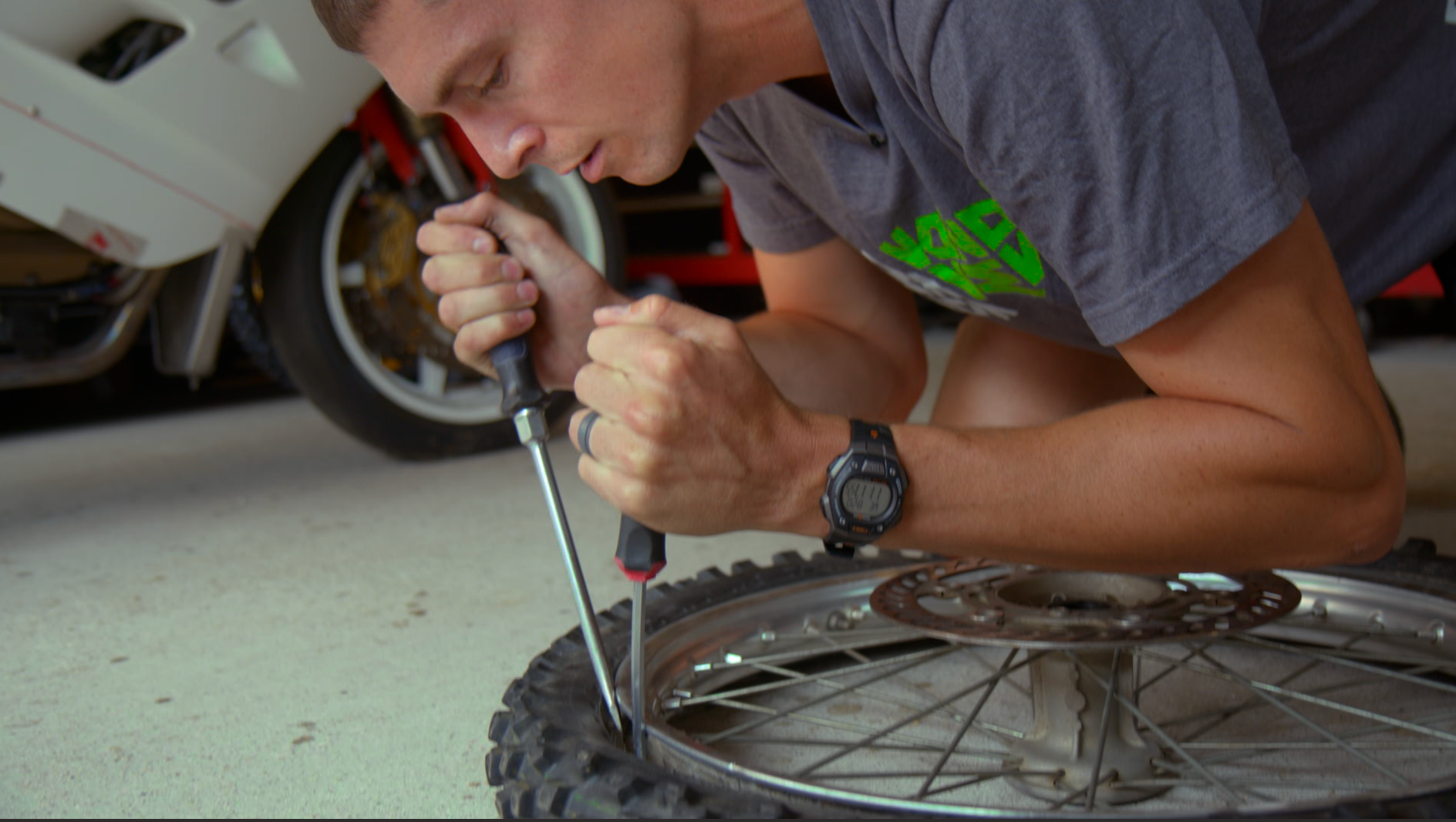 Rider using tire tools to change a motorcycle tire at home